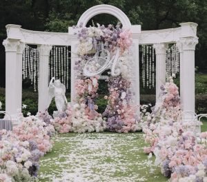 Luxurious outdoor wedding altar decoration with multiple pink and cream artificial floral arrangements